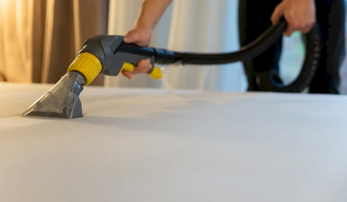 a hotel motel bed being vacuumed after stain removal