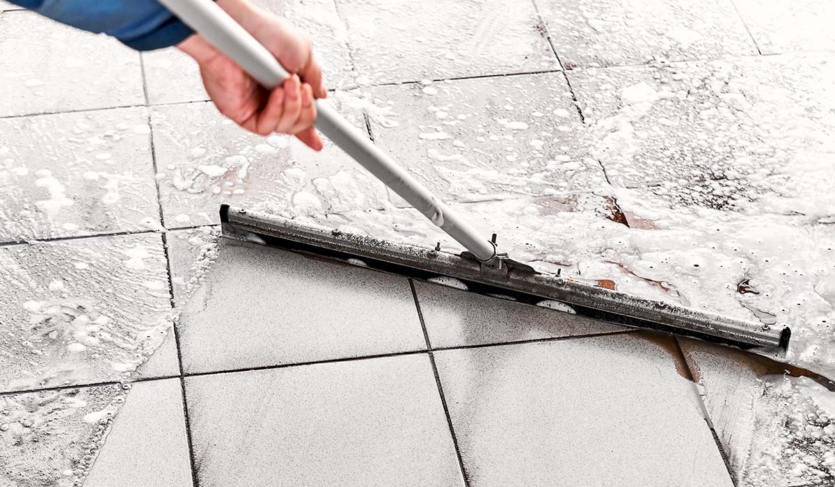 an employee removing water from a tile floor using a squeegee